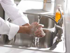 Man washing his hands with soap in a sink.