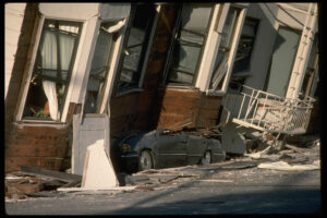 A car is crushed under the third story of an apartment building in San Francisco’s Marina District after the 1989 Loma Prieta quake. The ground levels are no longer visible because of structural failure and sinking due to liquefaction.