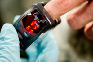 pulse oximeter showing oxygenation reading clamped on a white person's finger